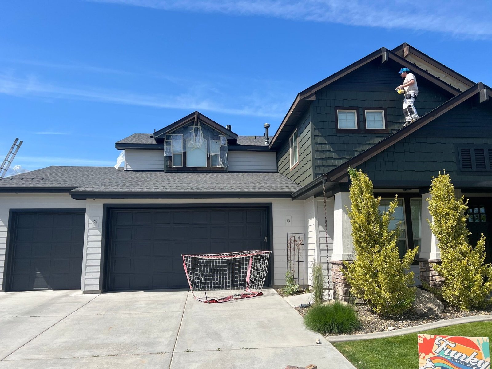 House exterior with painter on roof, detailed texture, and color contrast, showcasing professional painting service in Eagle, ID.