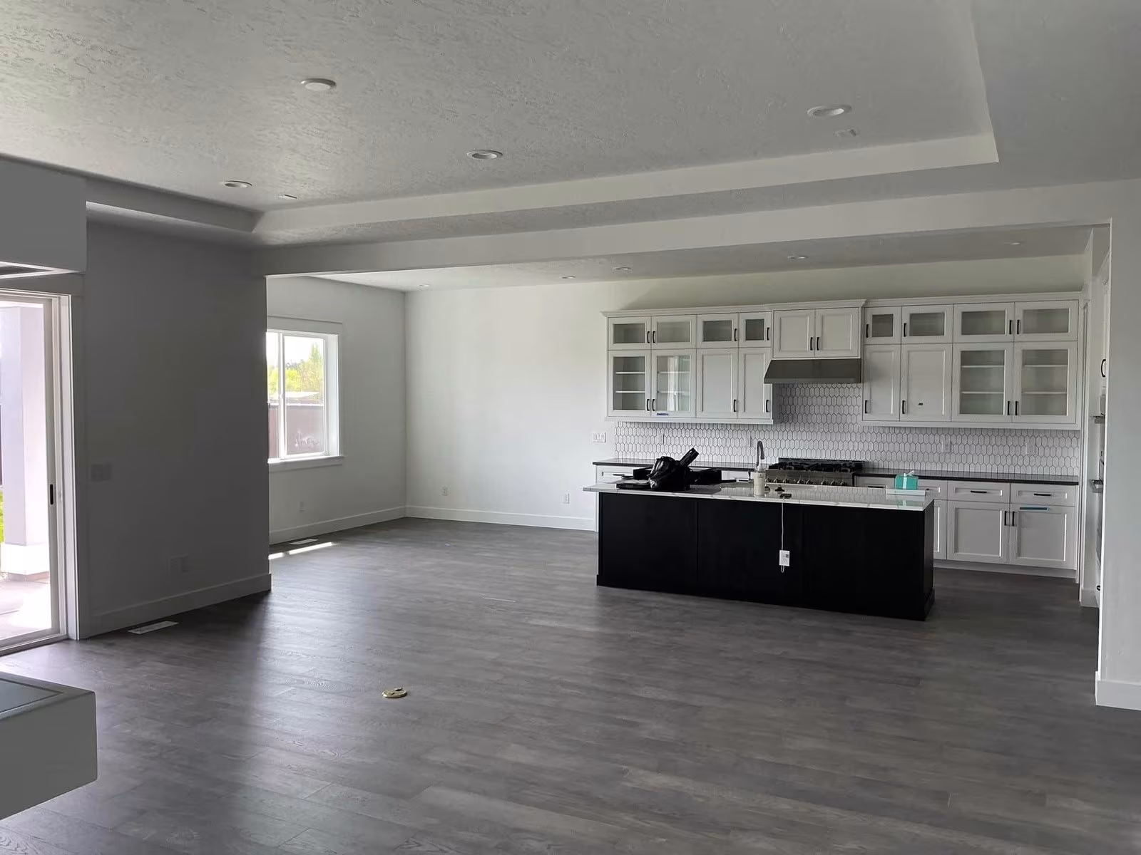 Spacious, well-lit interior of a modern kitchen and living area with gray flooring, white walls, and a black kitchen island, emphasizing the importance of ventilation for safe indoor painting.