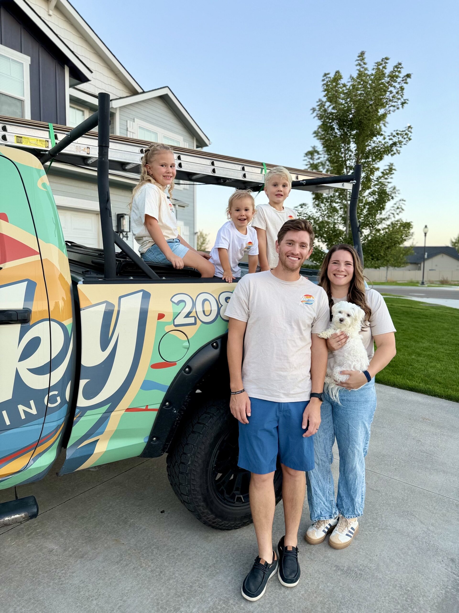 Family posing with a dog in front of a colorful Funky Painting truck, showcasing a friendly and professional painting service atmosphere in Boise, Idaho.