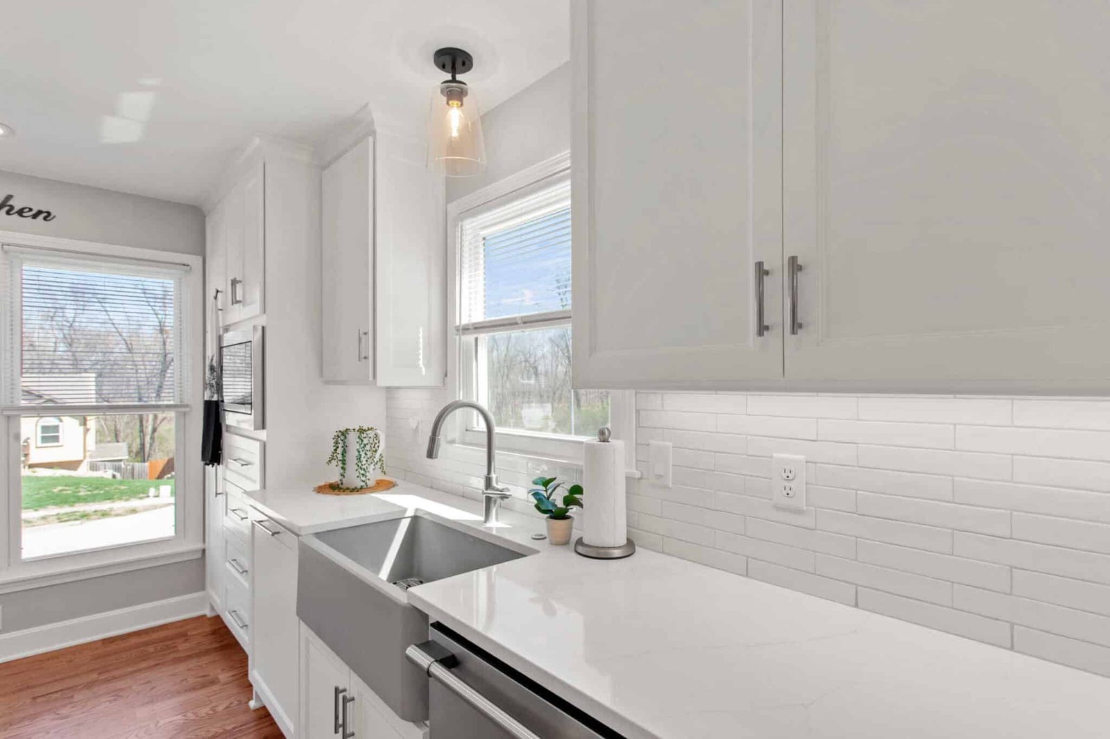 Modern kitchen interior featuring white cabinetry, stainless steel sink, and natural light through a window, highlighting a clean and inviting space ideal for interior painting and design considerations.