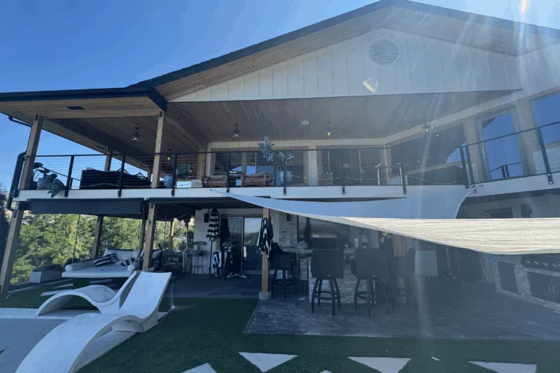 Residential exterior of a hillside home in Boise, ID, showcasing a blend of siding, stone, and brick, with a spacious deck, outdoor seating, and modern design elements.