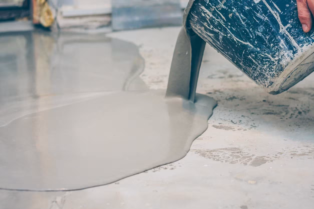 Pouring epoxy coating onto a concrete floor, showcasing a smooth, durable finish for residential and commercial spaces.