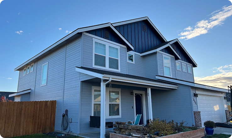Modern two-story home in Boise, Idaho, featuring a gray exterior, multiple windows, and a contrasting dark blue roof, showcasing quality exterior painting services.
