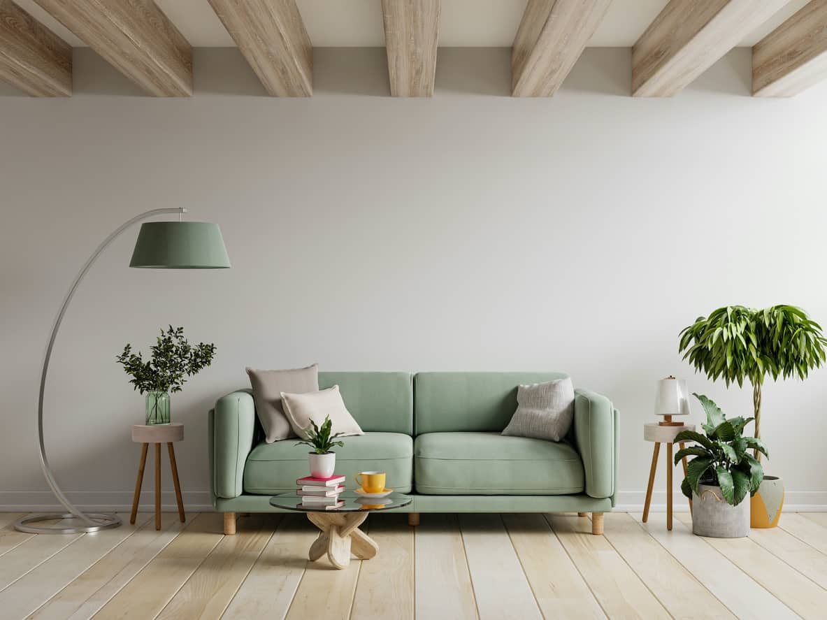 Modern interior living space featuring a light green sofa, stylish floor lamp, potted plants, and a wooden coffee table with books and cups, emphasizing interior design and painting choices.
