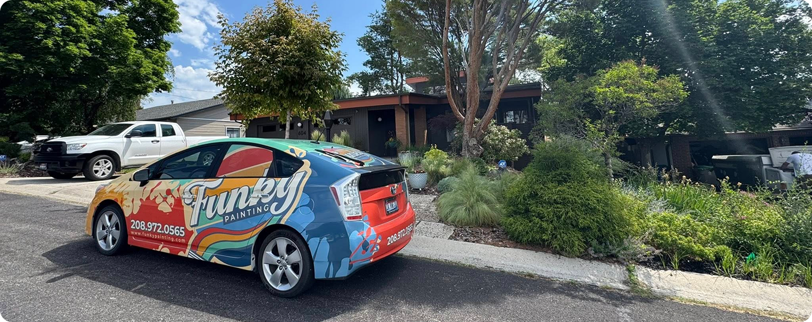 Funky Painting vehicle parked outside a residential property in Star, Idaho, showcasing vibrant branding and contact information, surrounded by lush greenery and a modern home.