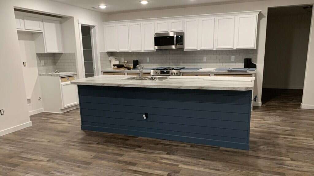 Kitchen cabinet refinishing in progress, with white cabinets and a navy shiplap island